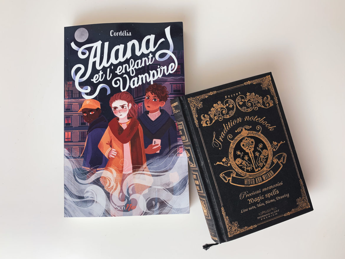 Alana et l'enfant vampire sur un fond blanc avec un carnet de notes noir et doré